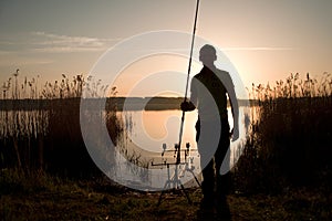 Fisherman silhouette at sunset near the lake