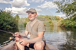 Fisherman sits in a boat with a spinning