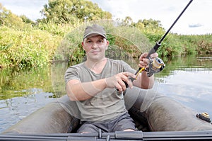 Fisherman sits in a boat with a spinning