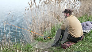 Fisherman sits and fishes on the shore. Man waiting a fish with a fishing rod.