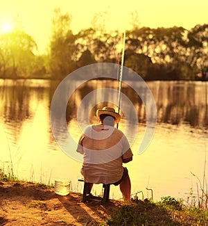 Fisherman sitting at beach sunset and fishing