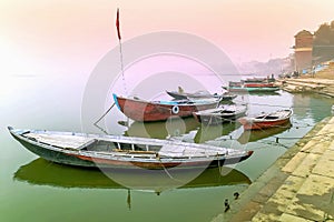 Fisherman sitting and fishing from colorful wooden boats in the morning mist on the holy rive Ganges at Varanasi