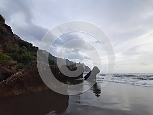 A fisherman sitting on a rock formation while big long waves flowing.