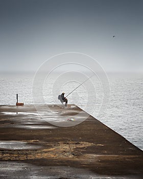 Fisherman sleeping on the pier on a foggy day at sea