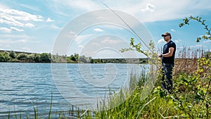 Fisherman with spinning rod on nature background. Angler man with fishing spinning or casting rod by the river