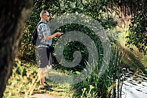 Fisherman with spinning rod on the summer lake. fisherman with spinning in his hands catching fish at sun day. Fisherman