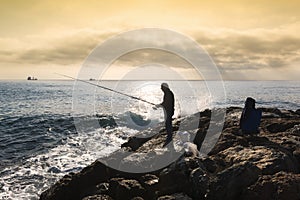 A fisherman standing with the fishing rod in his hand, he is on