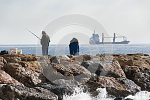 A fisherman standing with the fishing rod in his hand, he is on