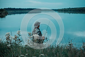 Fisherman standing in grass and fishing, back view