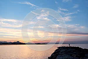 Fisherman standing on a pier at sunset