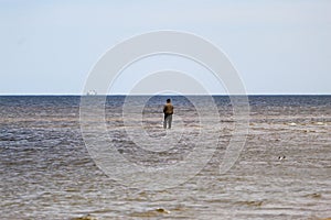 A fisherman stands aground in the sea bay and fishes