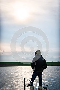 Fisherman in sunlight near two fishing rods waiting for the fish