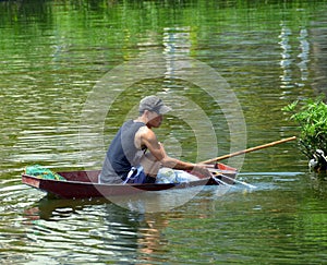 Fisherman tending his nets in a boat on West Lake in Hanoi.