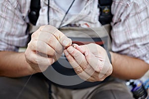 Fisherman threading a small fly onto his line