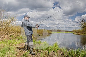 Fisherman throws spinning rod on the river bank