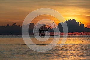 Fisherman on a traditional wooden boat during sunrise