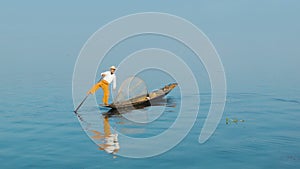 Fisherman turns a boat using paddles and feet. Inle lake, Burma (Myanmar)