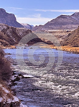 Fisherman upstream in Shoshone River views mountains leading into Yellowstone National Park from Cody, Wyoming in February winter. photo