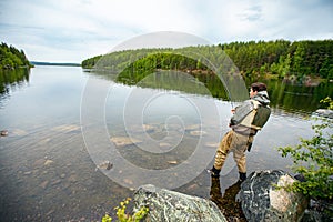 Fisherman using rod fly fishing in mountain river sunset