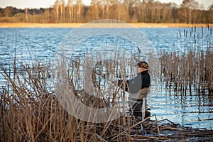 Fisherman in waders catches pike in the lake