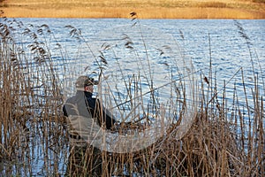 Fisherman in waders catches pike in the lake