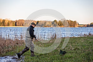 Fisherman in waders comes out of the river to the river bank