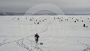 Fisherman walks on frozen lake, winter fishing championship, snowy lake