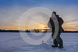 Fisherman winter fishing at dawn