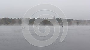 Fishermans in boats fishing in big misty fog