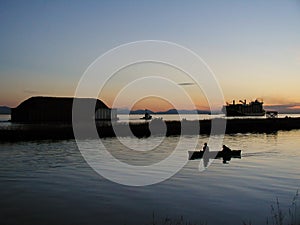 Fishermen in a boat, big container ship and tugboat towing a barge