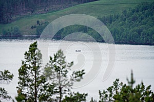 Fishermen in a boat are fishing on the river of Atna in Norway, photographed with telezoom