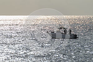 Fishermen on a boat off the coast of Livorno, Italy, in the early morning light