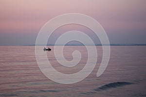 Fishermen on a boat at sea at sunrise.