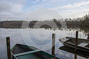 Fishermen boats in a lake during autumn time. Clouds reflecting on water