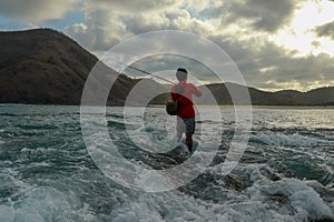 Fishermen catch fish at low tide. View from the back of guy with fishing rods in the water. Close up of Indonesian man