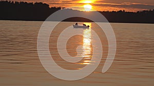 Fishermen check the nets on the forest lake at sunset