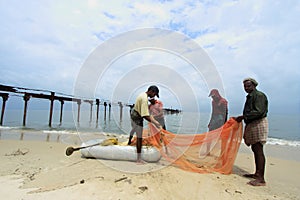 Fishermen clean fish net at seashore