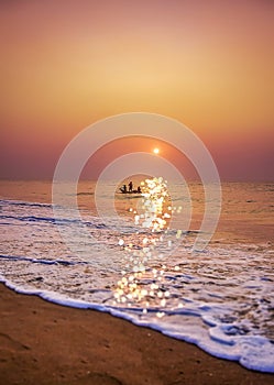 Fishermen coming back by boat to sea beach during early morning Sunrise time from the ocean.