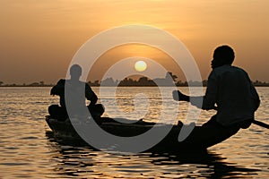 Fishermen crossing a lake at sunset photo