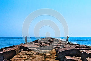 Fishermen fishing on jetty on clear sunny day