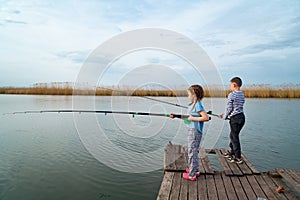 fishermen. little girl and boy fish on a fishing rod standing on a wooden bridge