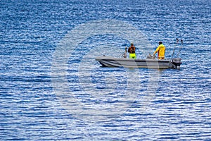 Fishermen in a motor boat in the middle of the bay near the shoreline on a calm day