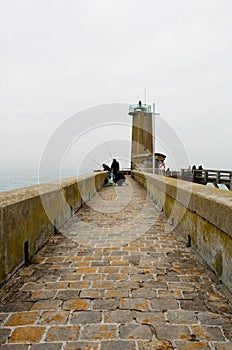 Fishermen on pier near a beacon light