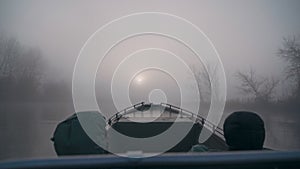 Fishermen ride the river in a boat in the fog in the morning