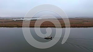 Fishermen riding boat blue for fishing in the morning foggy. View of the traditional houses fishermen built from bamboo