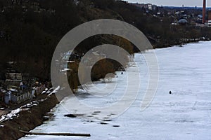 Fishermen on the river in winter ice fishing before