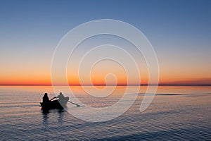 Fishermen rowing boat in se on sunrise