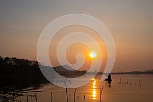 Fishermen\'s boats gently glide on the reservoir\'s calm waters during sunrise