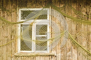 Fishermen`s nets are hung by the window of a wooden house