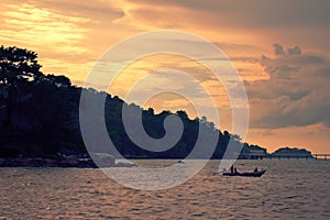 Fishermen sailing at sunset off the coast of Phuket, Thailand.